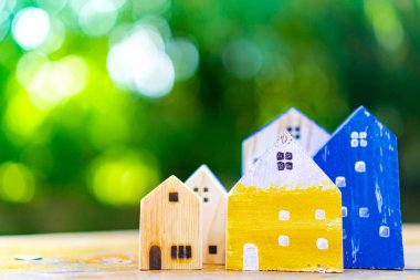 Güneş ışığı ve yeşil bokeh arka plan ile eski ahşap masa küçük ev modeli oyuncağa kadar kapalı.