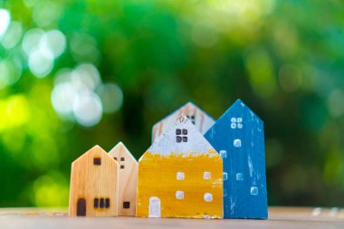 Güneş ışığı ve yeşil bokeh arka plan ile eski ahşap masa küçük ev modeli oyuncağa kadar kapalı.