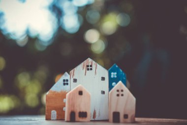Güneş ışığı ve yeşil bokeh arka plan ile eski ahşap masa küçük ev modeli oyuncağa kadar kapalı.