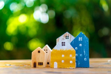 Güneş ışığı ve yeşil bokeh arka plan ile eski ahşap masa küçük ev modeli oyuncağa kadar kapalı.