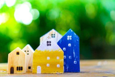 Güneş ışığı ve yeşil bokeh arka plan ile eski ahşap masa küçük ev modeli oyuncağa kadar kapalı.