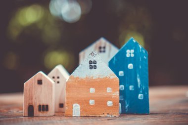 Güneş ışığı ve yeşil bokeh arka plan ile eski ahşap masa küçük ev modeli oyuncağa kadar kapalı.