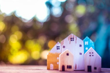 Güneş ışığı ve yeşil bokeh arka plan ile eski ahşap masa küçük ev modeli oyuncağa kadar kapalı.