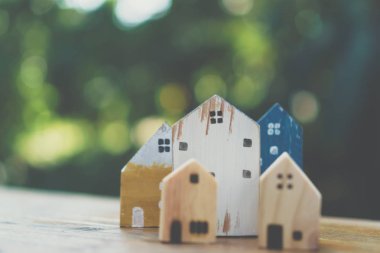Güneş ışığı ve yeşil bokeh arka plan ile eski ahşap masa küçük ev modeli oyuncağa kadar kapalı.