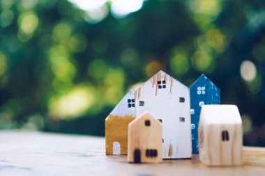 Güneş ışığı ve yeşil bokeh arka plan ile eski ahşap masa küçük ev modeli oyuncağa kadar kapalı.