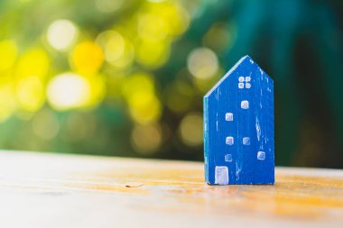 Güneş ışığı ve yeşil bokeh arka plan ile eski ahşap masa küçük ev modeli oyuncağa kadar kapalı.