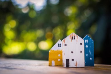 Güneş ışığı ve yeşil bokeh arka plan ile eski ahşap masa küçük ev modeli oyuncağa kadar kapalı.