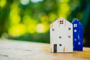 Güneş ışığı ve yeşil bokeh arka plan ile eski ahşap masa küçük ev modeli oyuncağa kadar kapalı.