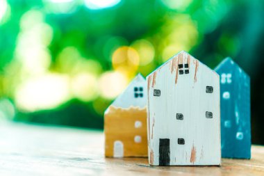 Güneş ışığı ve yeşil bokeh arka plan ile eski ahşap masa küçük ev modeli oyuncağa kadar kapalı.