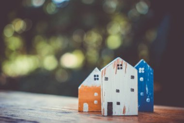 Güneş ışığı ve yeşil bokeh arka plan ile eski ahşap masa küçük ev modeli oyuncağa kadar kapalı.