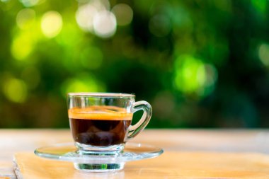 Siyah kahve ya da espresso film vintage sesi ve yeşil doğa bokeh arka plan ile ahşap masa üzerinde bir atış.