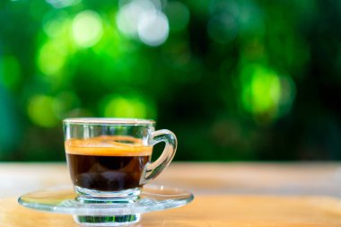 Siyah kahve ya da espresso film vintage sesi ve yeşil doğa bokeh arka plan ile ahşap masa üzerinde bir atış.