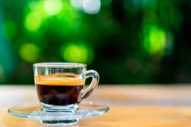Siyah kahve ya da espresso film vintage sesi ve yeşil doğa bokeh arka plan ile ahşap masa üzerinde bir atış.