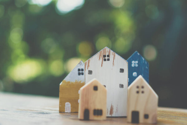 Closed up tiny home model toy on old wood table with sunlight  and green bokeh background.