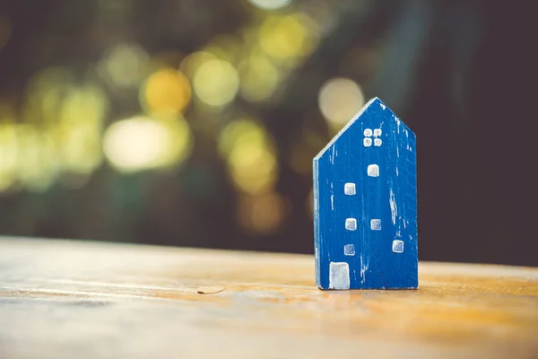 Closed up tiny home model toy on old wood table with sunlight  and green bokeh background.