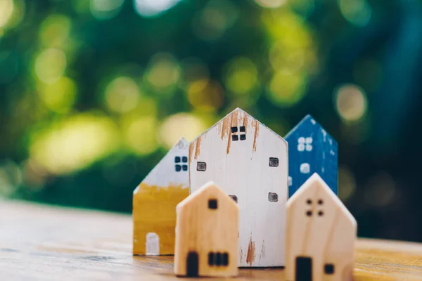 Closed up tiny home model toy on old wood table with sunlight  and green bokeh background.