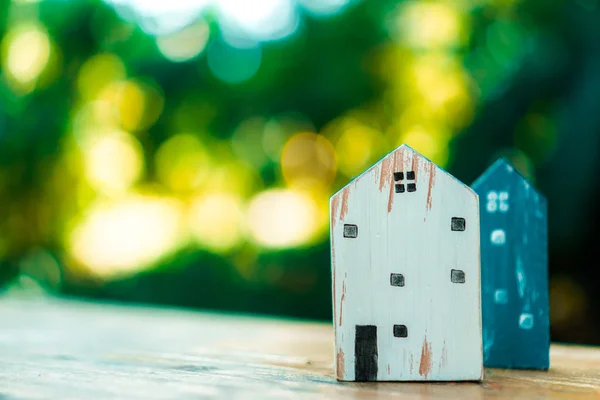 Closed up tiny home model toy on old wood table with sunlight  and green bokeh background.