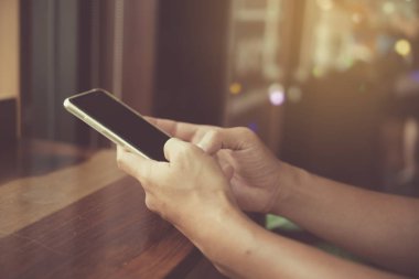 Kadın el Smartphone ile kafeterya salonu renkli güzel bokeh arka plan kullanarak. İş, finans, Ticaret hisse senedi maket ve sosyal ağ kavramı.