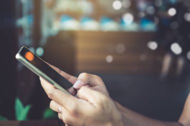 Kadın el Smartphone ile kafeterya salonu renkli güzel bokeh arka plan kullanarak. İş, finans, Ticaret hisse senedi maket ve sosyal ağ kavramı.