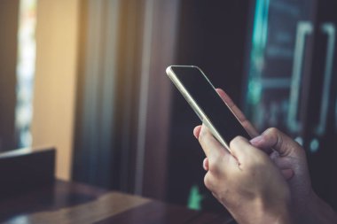 Kadın el Smartphone ile kafeterya salonu renkli güzel bokeh arka plan kullanarak. İş, finans, Ticaret hisse senedi maket ve sosyal ağ kavramı.