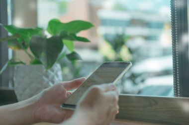 Kadın el Smartphone ile kafeterya salonu renkli güzel bokeh arka plan kullanarak. İş, finans, Ticaret hisse senedi maket ve sosyal ağ kavramı.