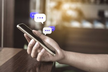 Kadınlar akıllı telefon daktiloyla yazı yazıp sohbet ediyorlar. Sohbet kutusu simgeleri ortaya çıkıyor. Sosyal medya teknolojisi kavramı. Klasik yumuşak renk tonu arkaplanı.