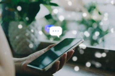 Kadınlar akıllı telefon daktiloyla yazı yazıp sohbet ediyorlar. Sohbet kutusu simgeleri ortaya çıkıyor. Sosyal medya teknolojisi kavramı. Klasik yumuşak renk tonu arkaplanı.