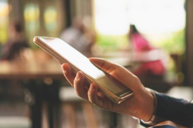Kadın el kafe salonu arka planda Smartphone kullanarak. İş, finans, Ticaret hisse senedi maket ve sosyal ağ kavramı.