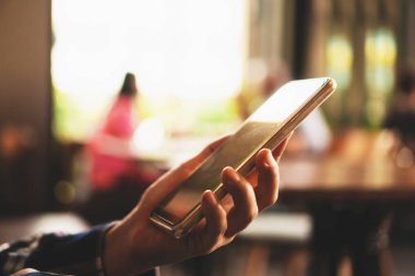 Kadın el kafe salonu arka planda Smartphone kullanarak. İş, finans, Ticaret hisse senedi maket ve sosyal ağ kavramı.