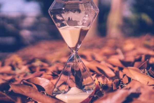 Small hourglass show time is flowing on old wood grunge texture. — Stock Photo, Image