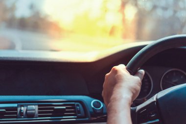 Direksiyon simidi üzerinde adamın elini arka plan ile bir araba.