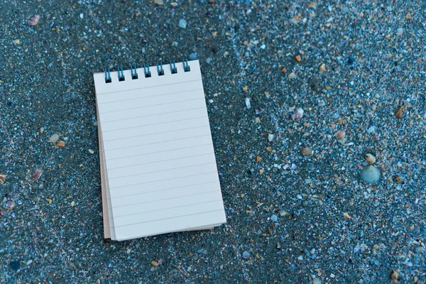 Piccolo notebook bianco su sabbia a bella struttura di mare di spiaggia . — Foto Stock