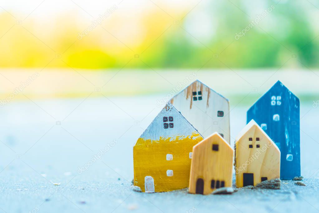 Closed up tiny home models on sand with sunlight and beach.