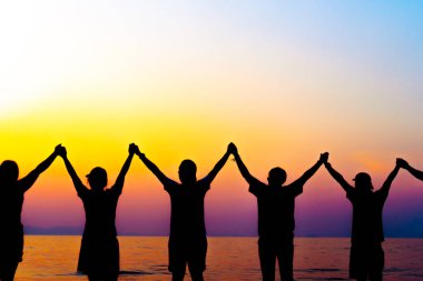 Bir grup kadın rise eller gökyüzü özgürlük kavramı mavi gökyüzü ve plaj gün batımı kadar.