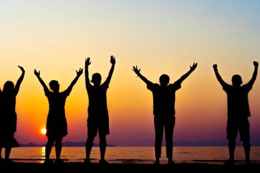 Bir grup kadın rise eller gökyüzü özgürlük kavramı mavi gökyüzü ve plaj gün batımı kadar.