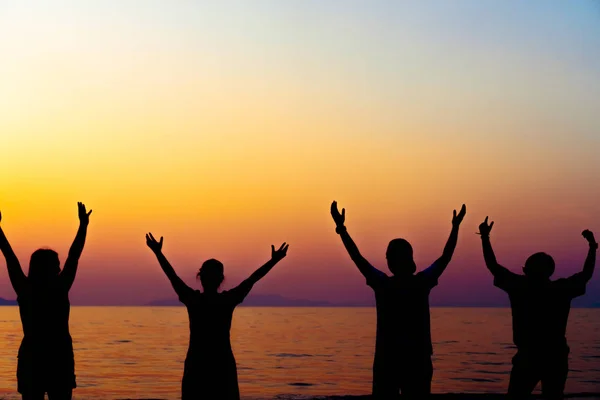 A group of women rise hands up to sky freedom concept with blue sky and beach sunset. — Stock Photo, Image