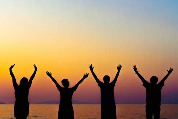 A group of women rise hands up to sky freedom concept with blue sky and beach sunset. — Stock Photo, Image