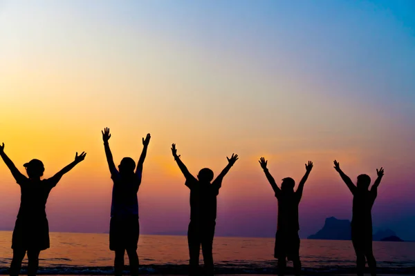 A group of women rise hands up to sky freedom concept with blue sky and beach sunset. — Stock Photo, Image