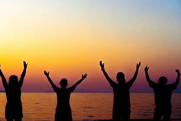 A group of women rise hands up to sky freedom concept with blue sky and beach sunset. Stock Image