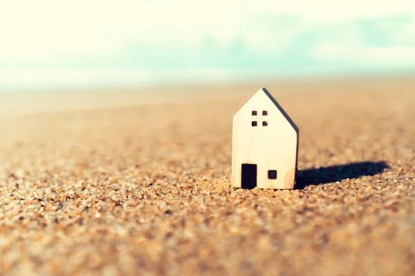 Closed up tiny home models on sand with sunlight and beach.