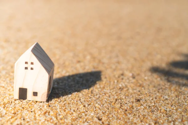 Closed up tiny home models on sand with sunlight and beach.