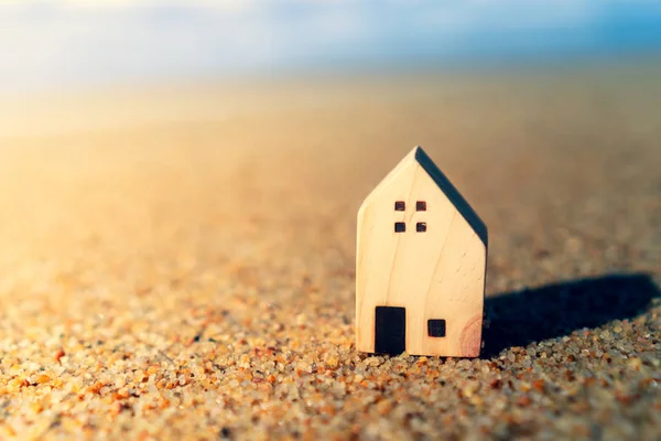 Cerrado pequeños modelos de casa en la arena con la luz del sol y la playa . — Foto de Stock
