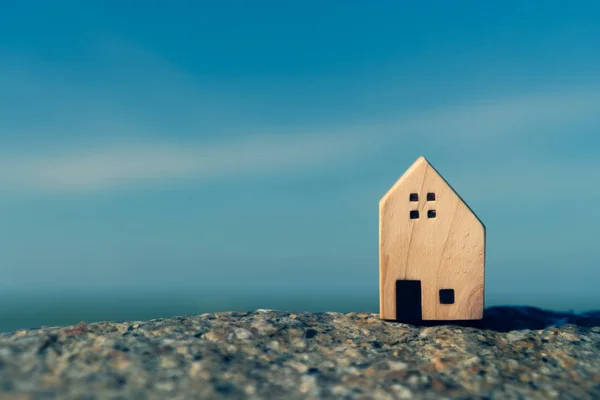 Closed up tiny home models on sand with sunlight and beach.