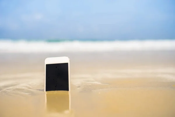 Smartphone na piasku tropikalnej letniej plaży w dniu wakacji. — Zdjęcie stockowe