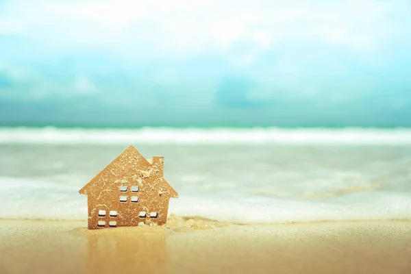 Closed up tiny home models on sand with sunlight and beach.