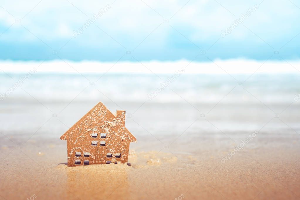 Closed up tiny home models on sand with sunlight and beach.