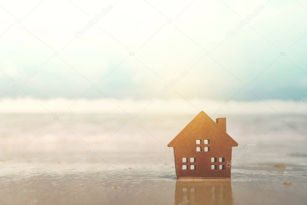 Closed up tiny home models on sand with sunlight and beach.