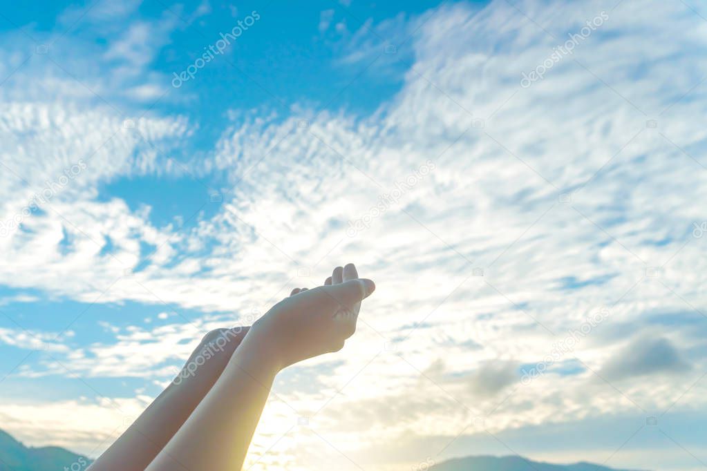 Woman hands place together like praying in front of nature green  background.