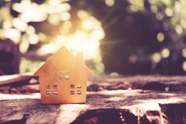 Güneş ışığı yeşil bokeh arka plan ile katta veya ahşap tahta üzerinde küçük ev modeli kapalı. Yaşam veya yatırım konsepti için ev mülkiyet.