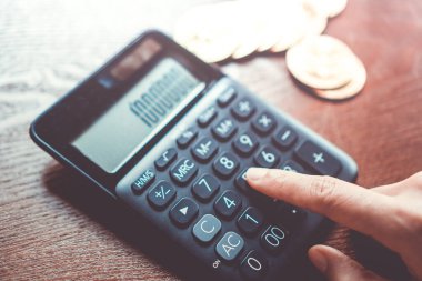 Kadın, gelecekte arka plan olarak blok zinciri içinde kripto para dijital sembolü olarak bir yığın Bitcoin para ile hesap makinesi kullanır.